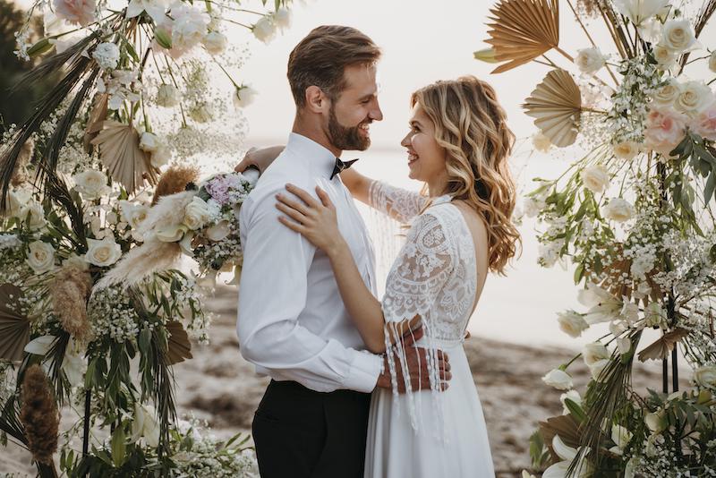 Des mariés se regardant yeux dans les yeux entourés de fleurs lors d’un mariage romantique
